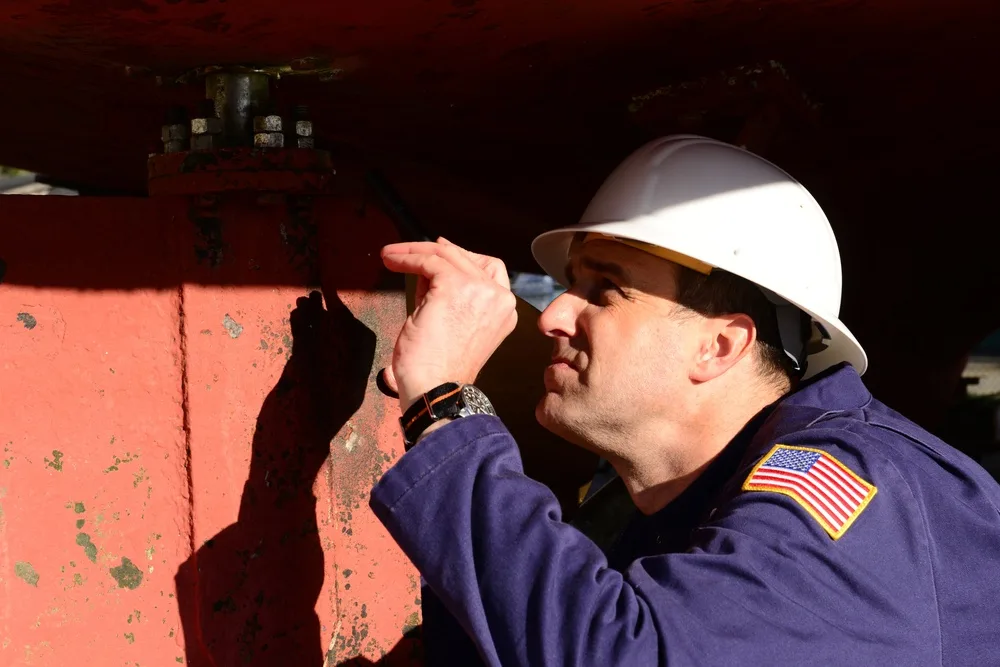 A U.S. Coast Guard marine inspector examines a vessel’s rudder in dry dock